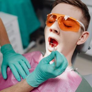 A patient receiving dental care while wearing protective eyewear in a clinic setting.